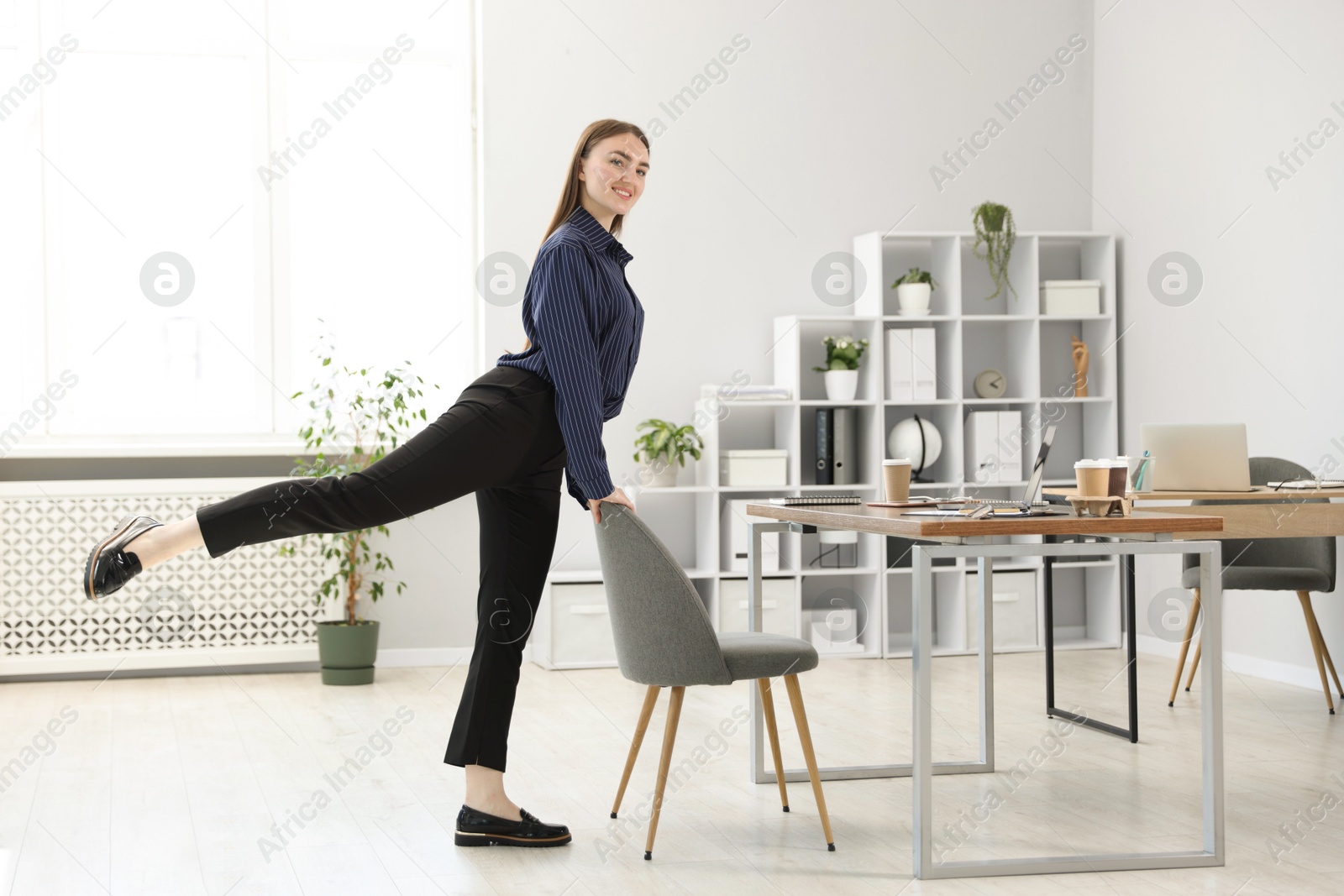 Beautiful woman exercising with chair in office Photo of Beautiful woman exercising with chair in office