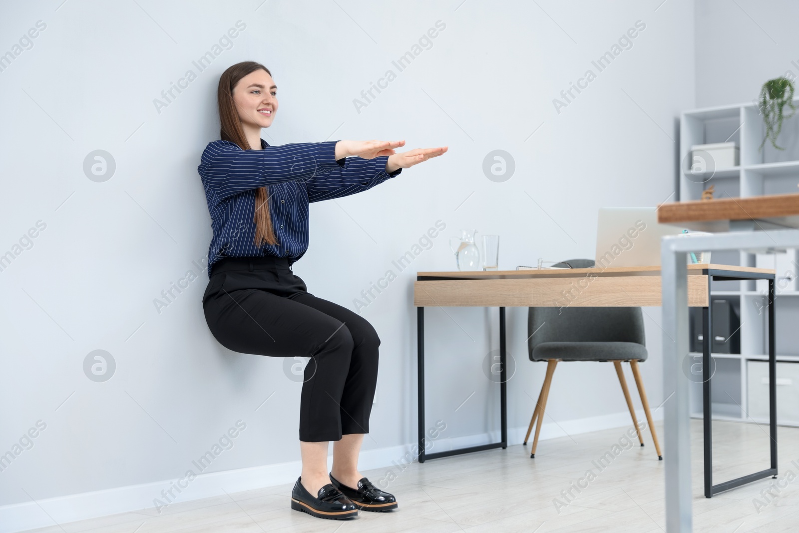 Beautiful woman doing exercise near wall in office Photo of Beautiful woman doing exercise near wall in office