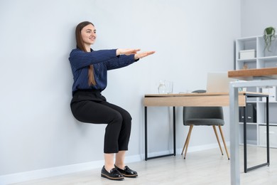 Photo of Beautiful woman doing exercise near wall in office