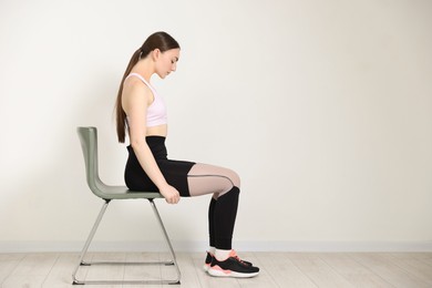 Photo of Beautiful woman stretching on chair at home, space for text