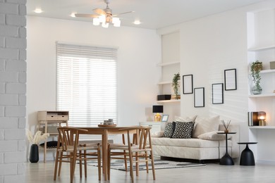 Photo of Table, chairs and comfortable sofa indoors. Interior design