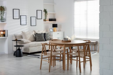 Photo of Table, chairs and comfortable sofa indoors. Interior design