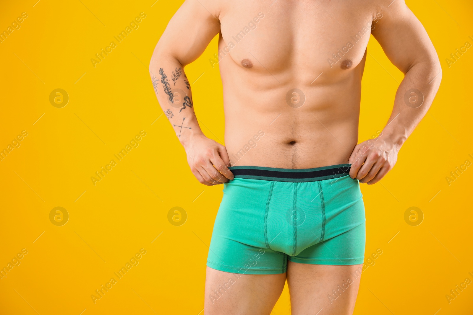 Young man in stylish turquoise underwear on orange background, closeup. Space for text Photo of Young man in stylish turquoise underwear on orange background, closeup. Space for text