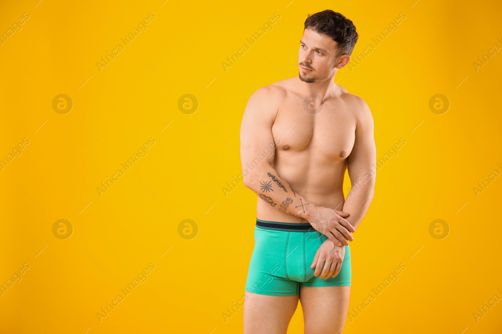 Young man in stylish turquoise underwear on orange background. Space for text Photo of Young man in stylish turquoise underwear on orange background. Space for text