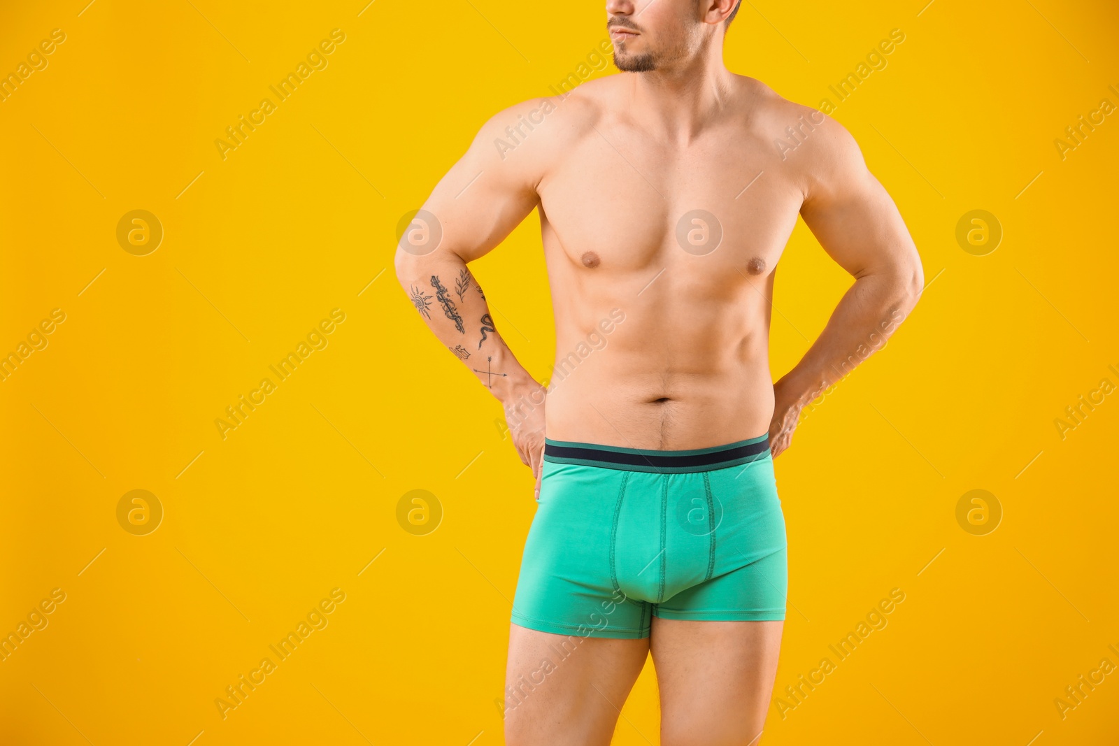 Young man in stylish turquoise underwear on orange background, closeup Photo of Young man in stylish turquoise underwear on orange background, closeup