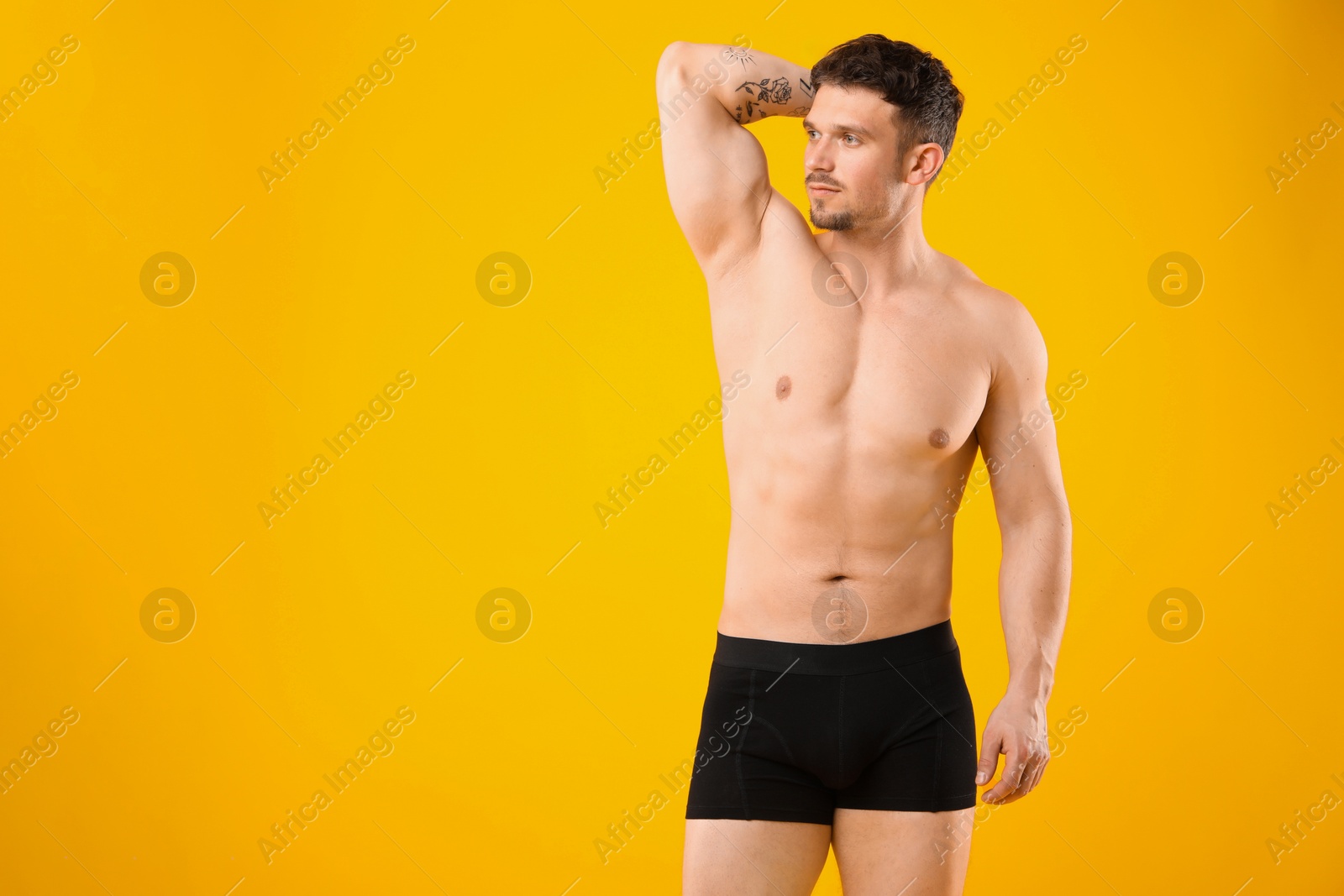 Young man in stylish black underwear on orange background. Space for text Photo of Young man in stylish black underwear on orange background. Space for text