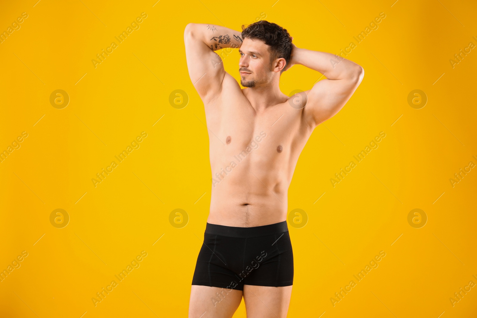 Young man in stylish black underwear on orange background Photo of Young man in stylish black underwear on orange background