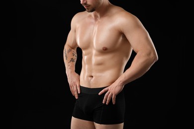 Photo of Young man in stylish underwear on black background, closeup