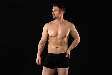 Photo of Young man in stylish underwear on black background