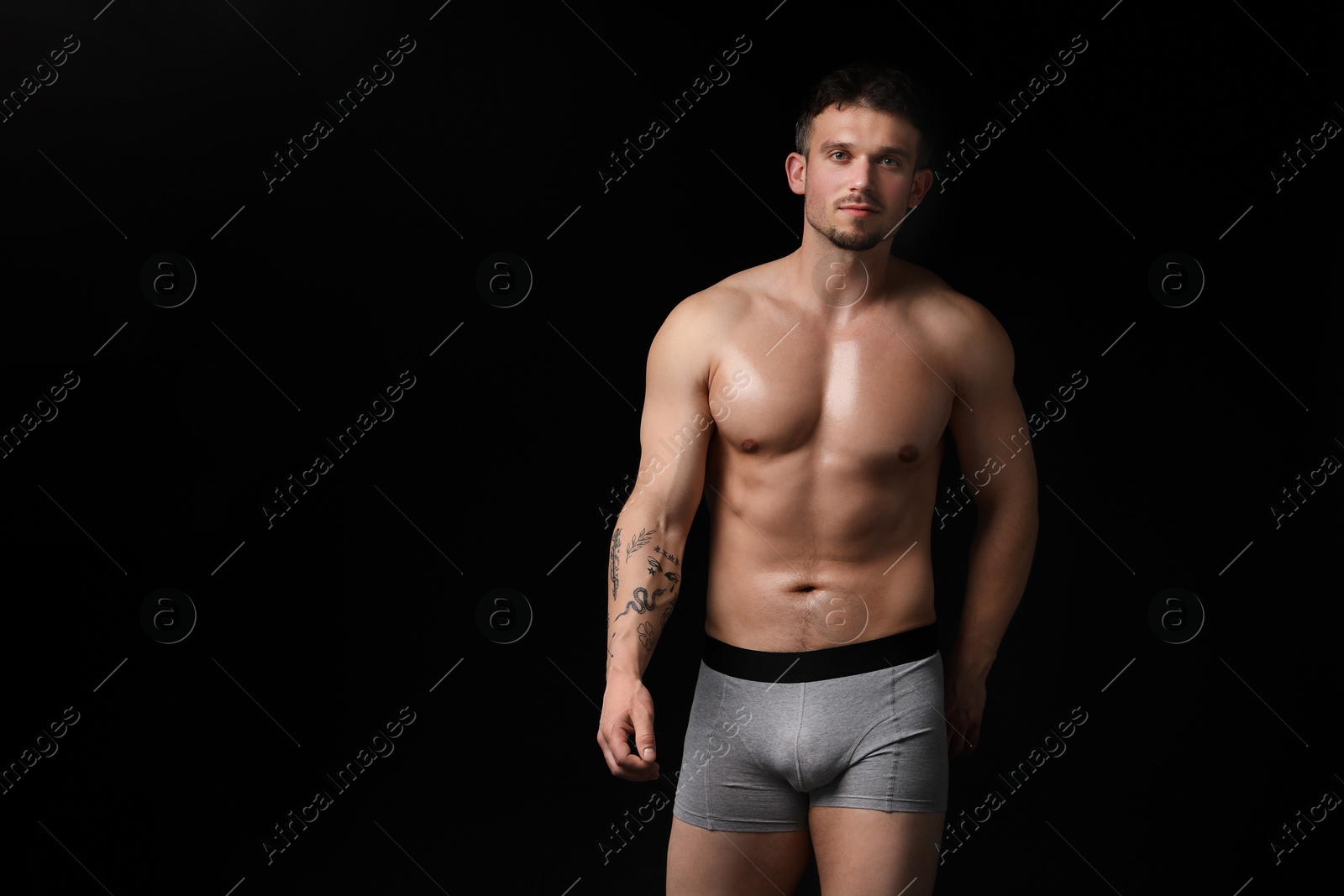 Young man in stylish light grey underwear on black background. Space for text Photo of Young man in stylish light grey underwear on black background. Space for text