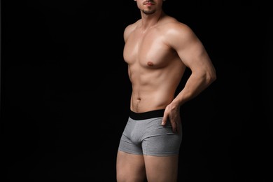 Photo of Young man in stylish light grey underwear on black background, closeup