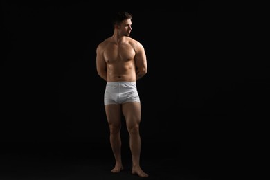 Photo of Young man in stylish white underwear on black background