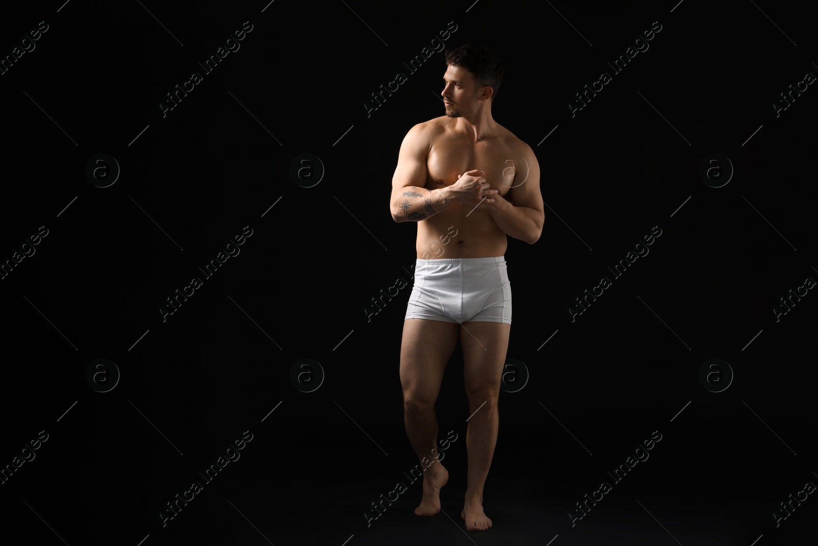 Young man in stylish white underwear on black background Photo of Young man in stylish white underwear on black background