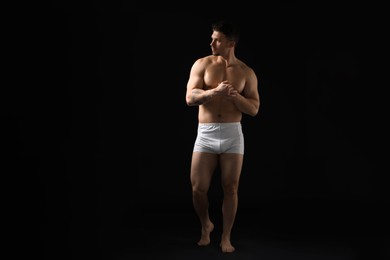 Photo of Young man in stylish white underwear on black background