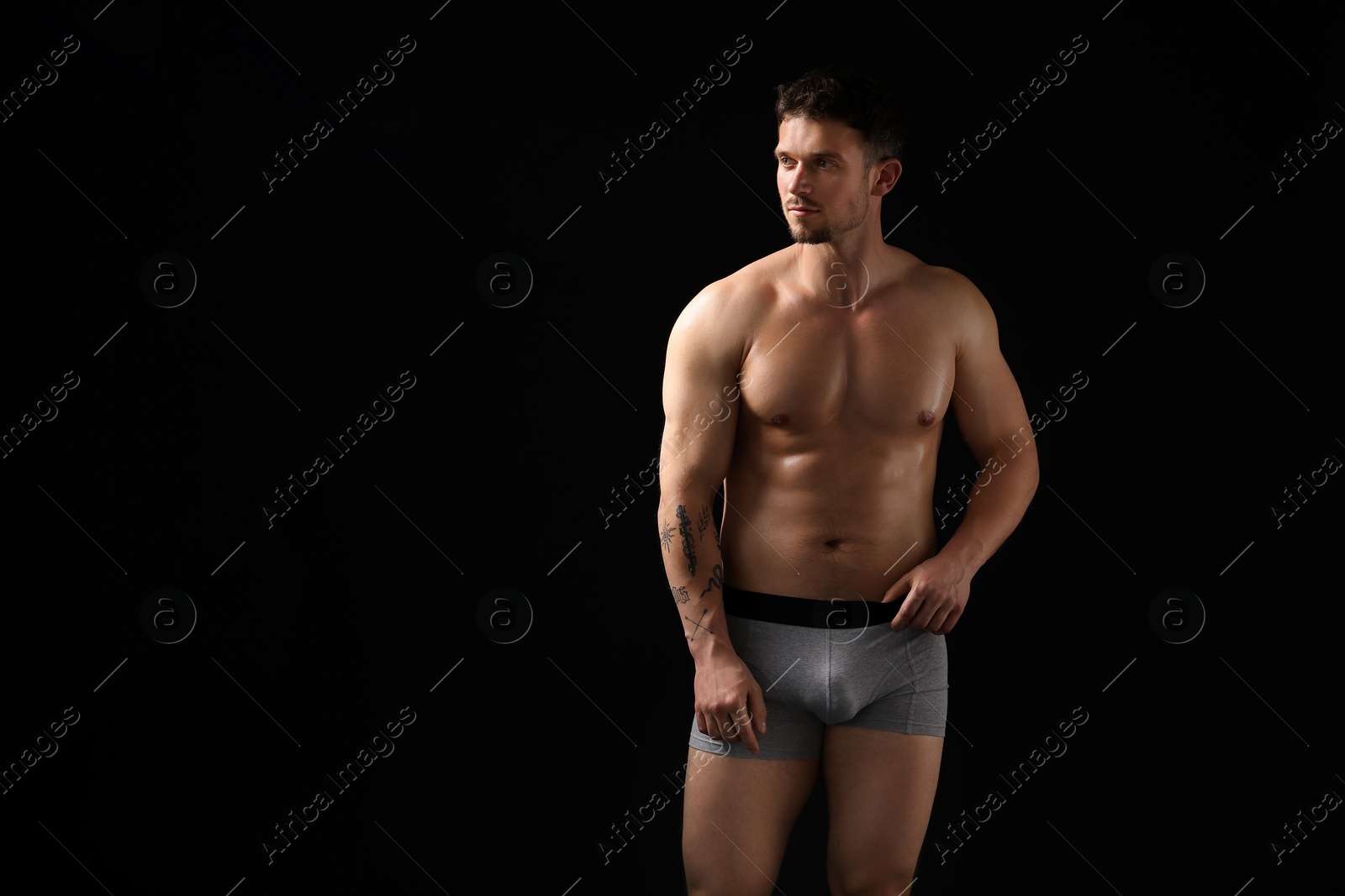 Young man in stylish light grey underwear on black background. Space for text Photo of Young man in stylish light grey underwear on black background. Space for text