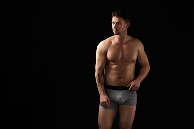 Photo of Young man in stylish light grey underwear on black background. Space for text
