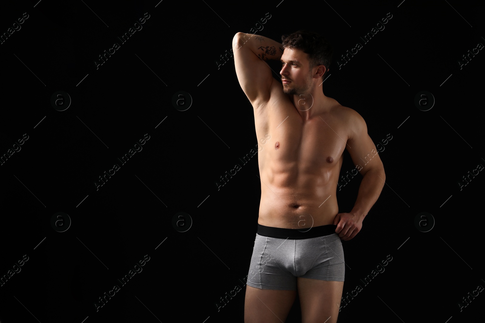 Young man in stylish light grey underwear on black background. Space for text Photo of Young man in stylish light grey underwear on black background. Space for text