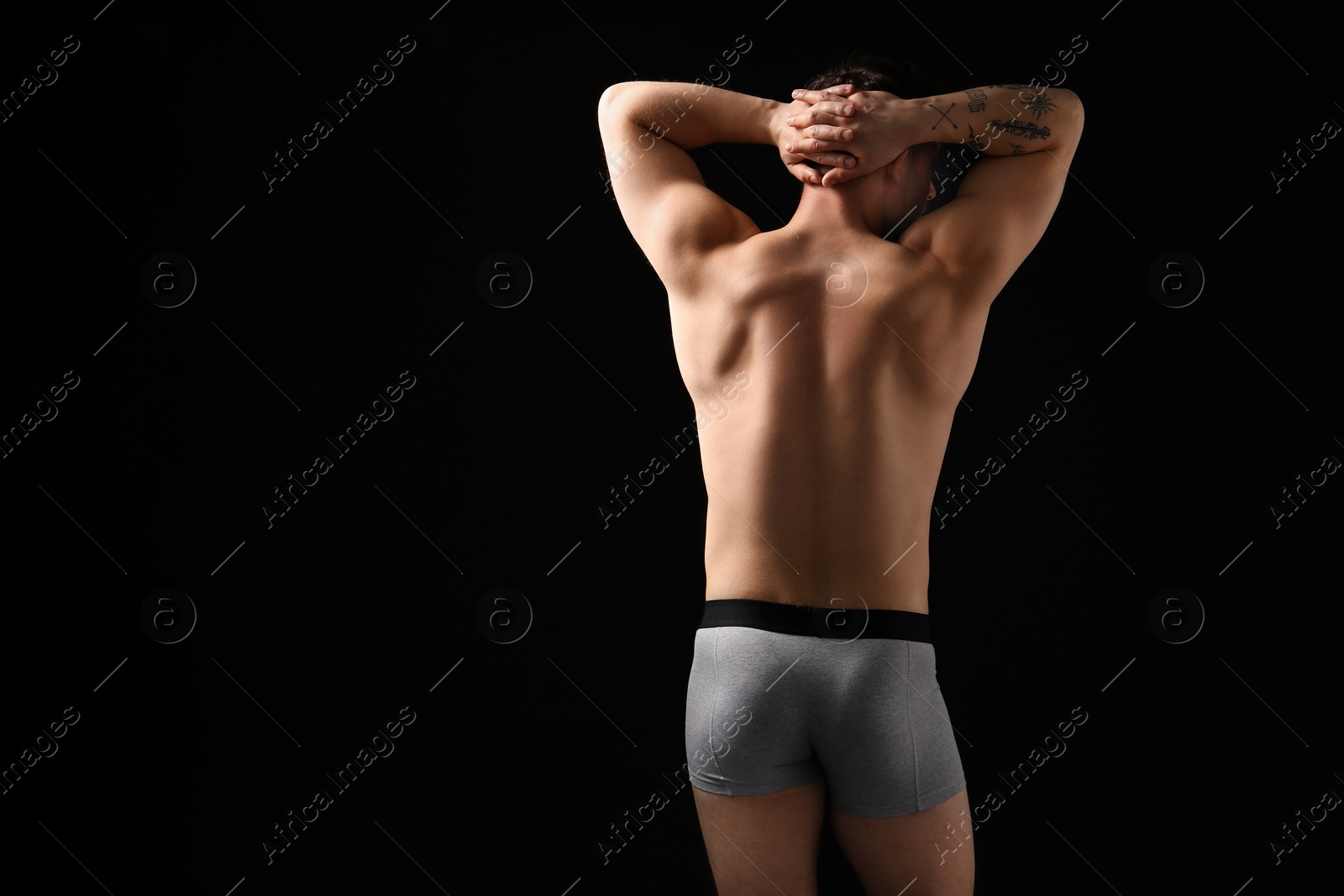 Young man in stylish light grey underwear on black background, back view. Space for text Photo of Young man in stylish light grey underwear on black background, back view. Space for text