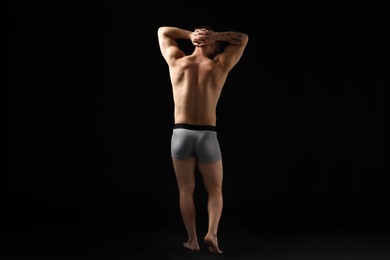 Photo of Young man in stylish light grey underwear on black background, back view