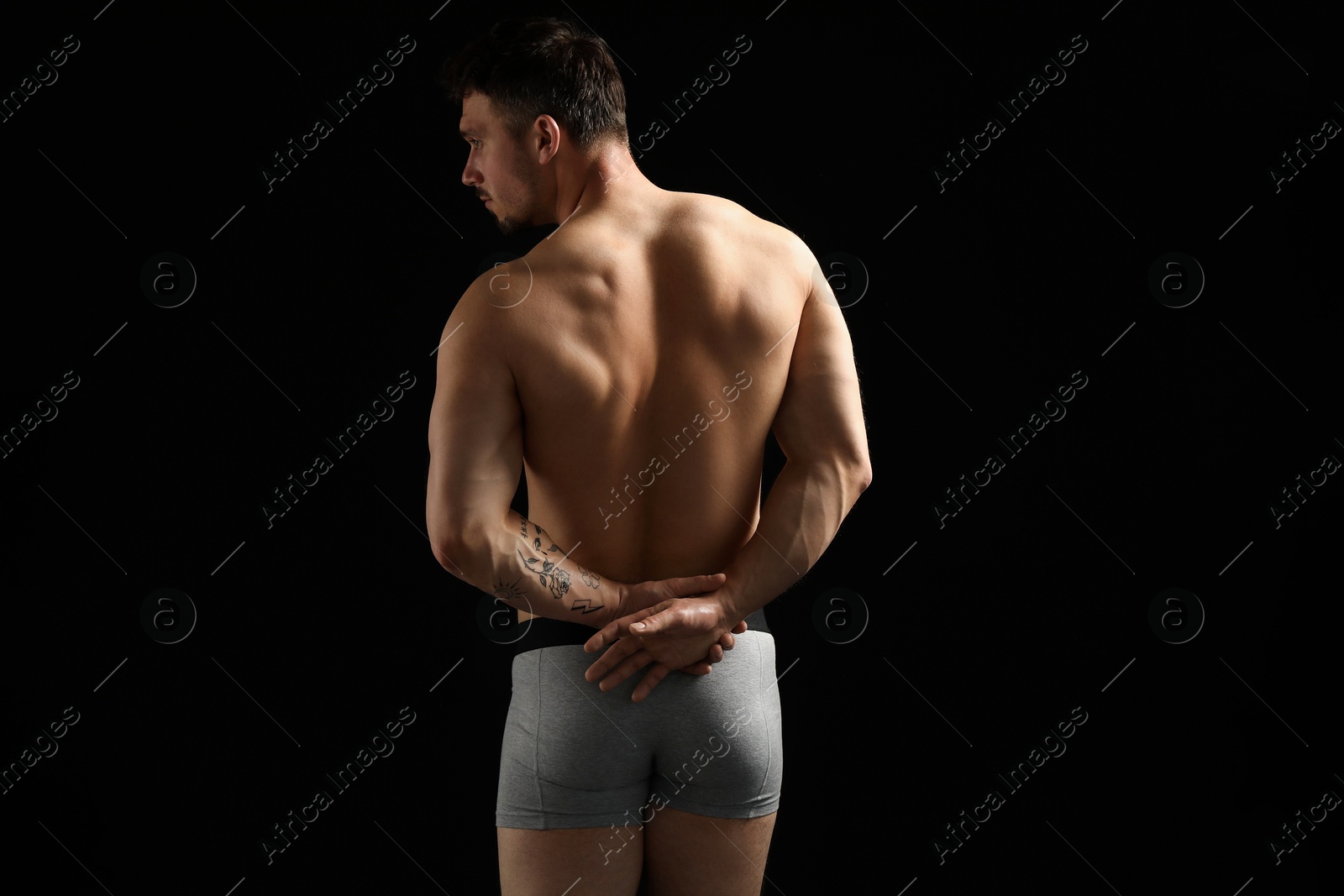 Young man in stylish light grey underwear on black background, back view Photo of Young man in stylish light grey underwear on black background, back view
