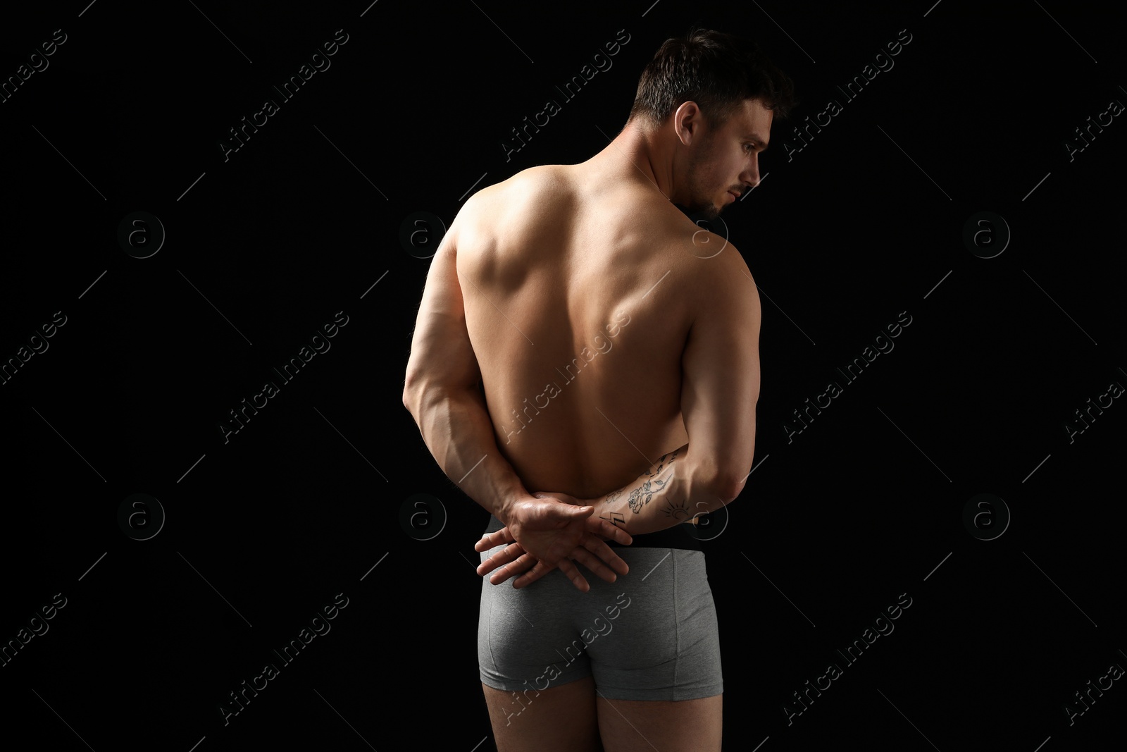 Young man in stylish light grey underwear on black background, back view Photo of Young man in stylish light grey underwear on black background, back view