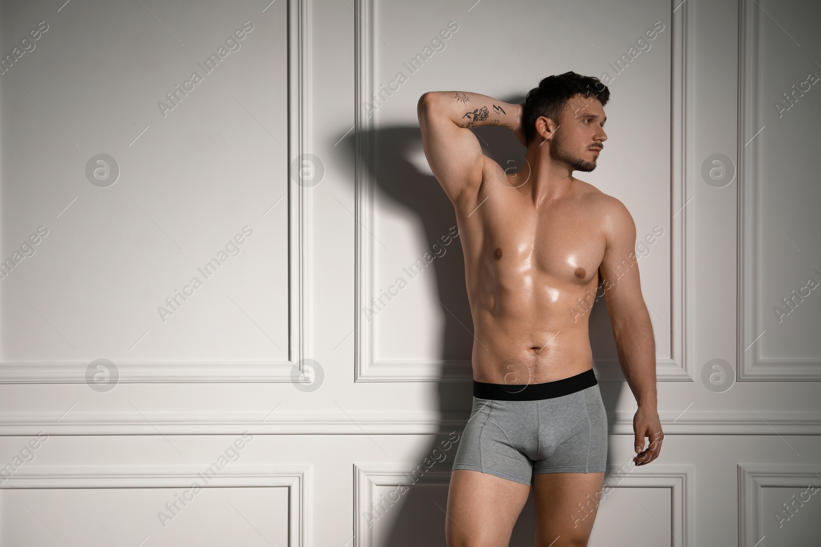 Young man in stylish light grey underwear near white wall indoors. Space for text Photo of Young man in stylish light grey underwear near white wall indoors. Space for text