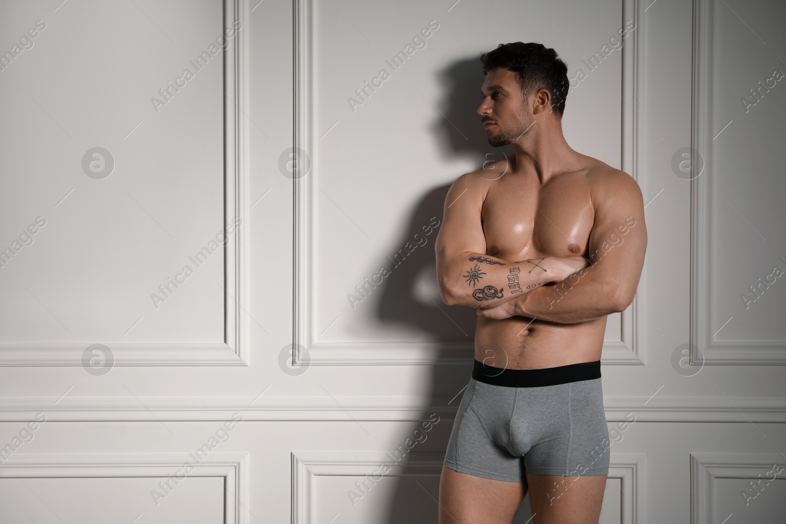 Young man in stylish light grey underwear near white wall indoors. Space for text Photo of Young man in stylish light grey underwear near white wall indoors. Space for text