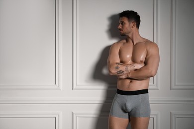 Photo of Young man in stylish light grey underwear near white wall indoors. Space for text