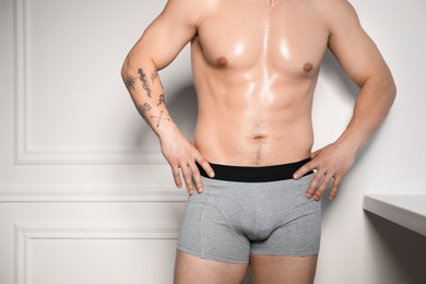 Photo of Young man in stylish light grey underwear near white wall indoors, closeup