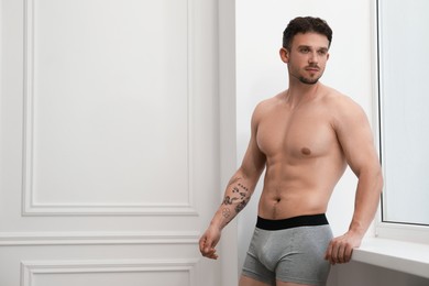 Photo of Young man in stylish light grey underwear near white wall indoors. Space for text