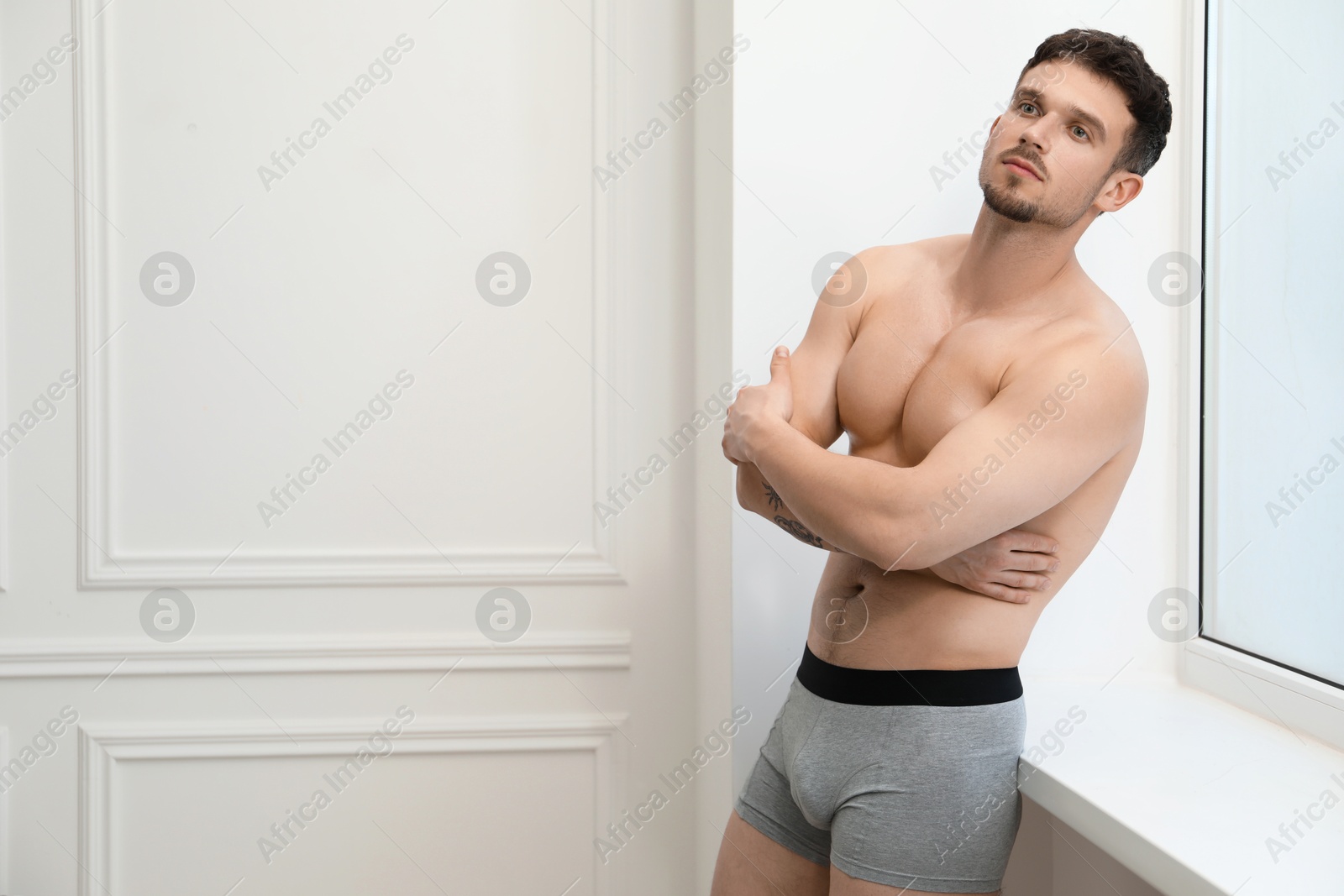 Young man in stylish light grey underwear near white wall indoors. Space for text Photo of Young man in stylish light grey underwear near white wall indoors. Space for text