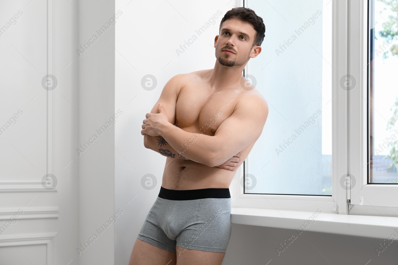 Young man in stylish light grey underwear near white wall indoors Photo of Young man in stylish light grey underwear near white wall indoors