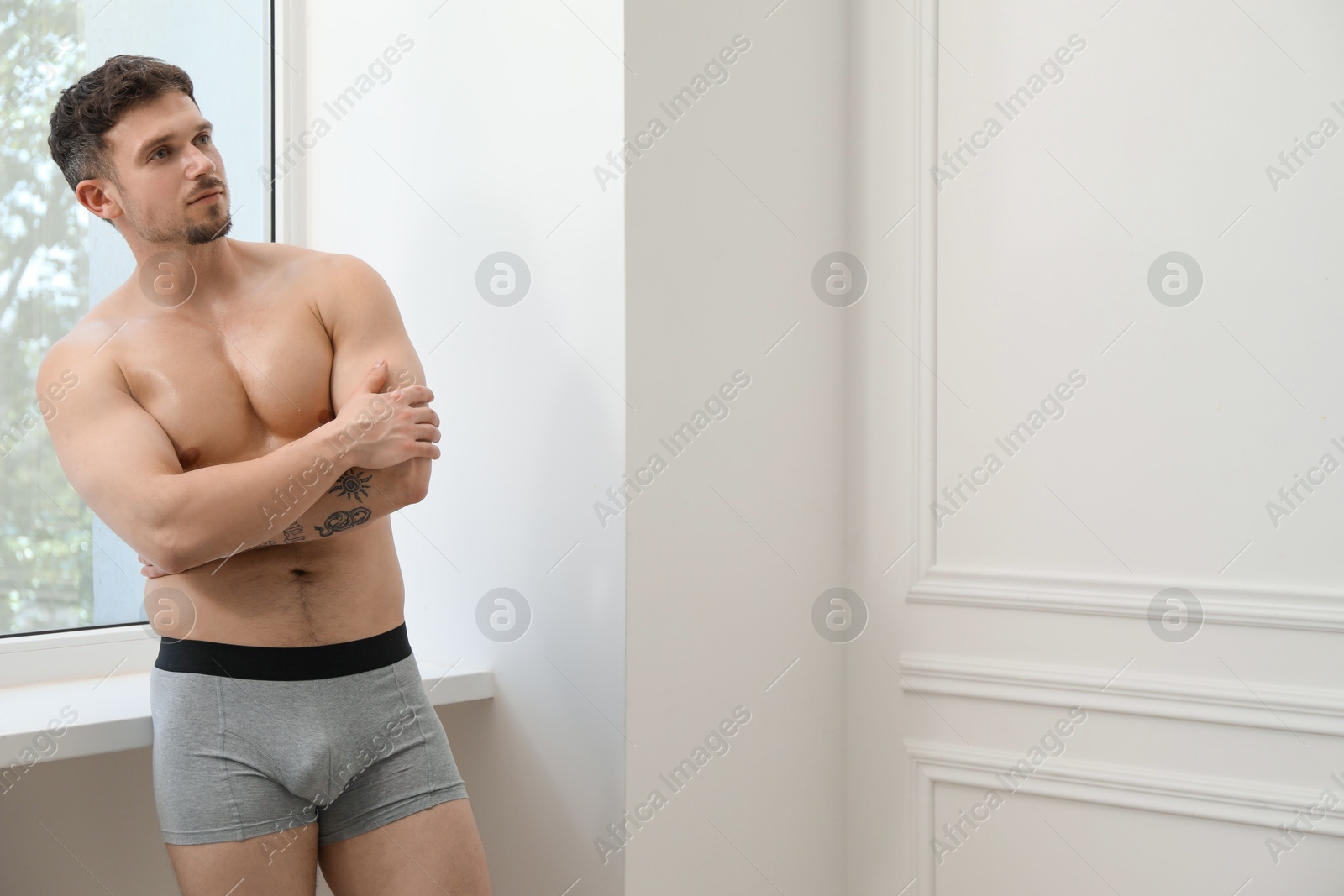 Young man in stylish light grey underwear near white wall indoors. Space for text Photo of Young man in stylish light grey underwear near white wall indoors. Space for text
