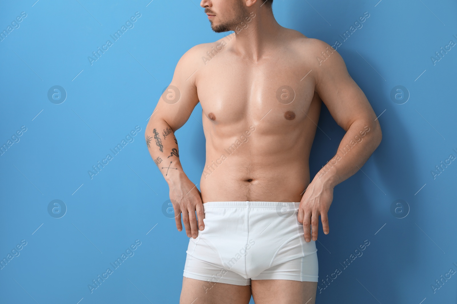 Young man in stylish white underwear on light blue background, closeup Photo of Young man in stylish white underwear on light blue background, closeup