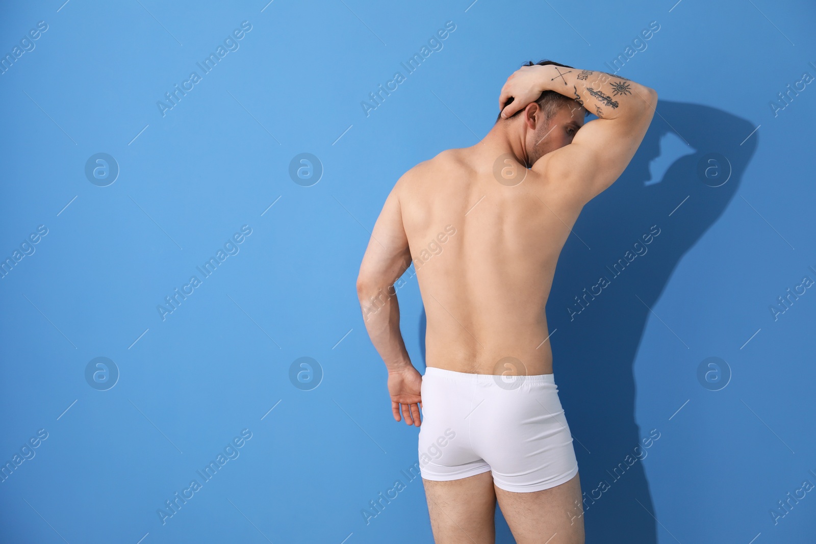 Young man in stylish white underwear on light blue background, back view. Space for text Photo of Young man in stylish white underwear on light blue background, back view. Space for text