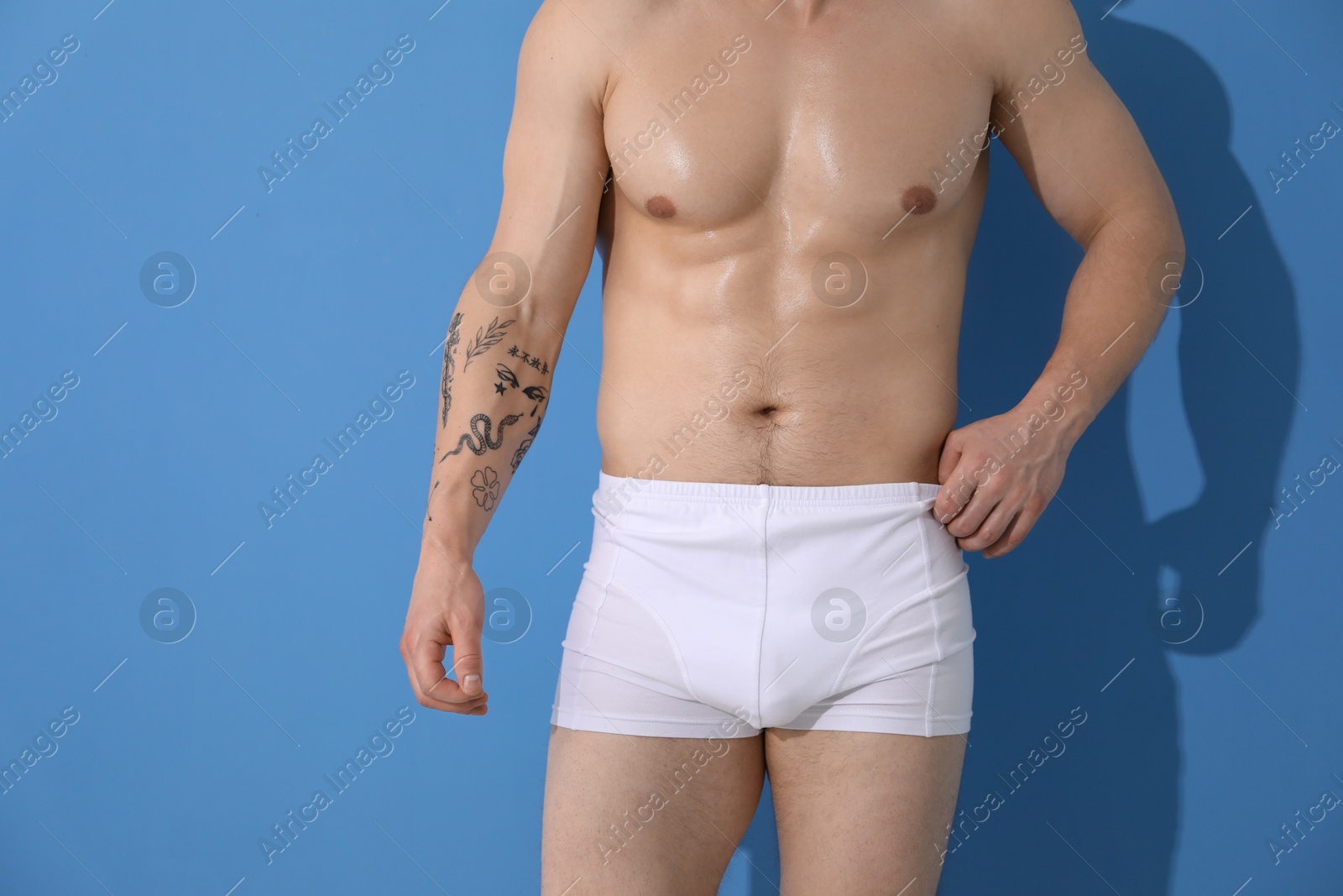 Young man in stylish white underwear on light blue background, closeup Photo of Young man in stylish white underwear on light blue background, closeup