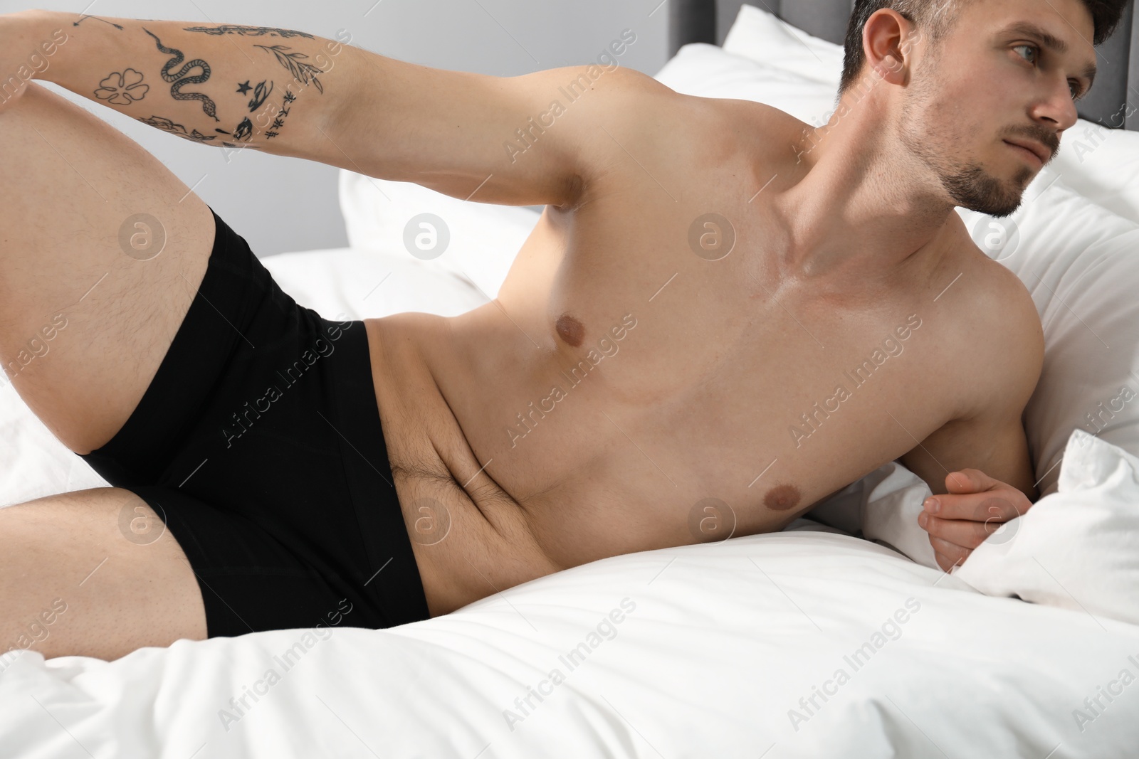 Young man in stylish black underwear on bed indoors Photo of Young man in stylish black underwear on bed indoors