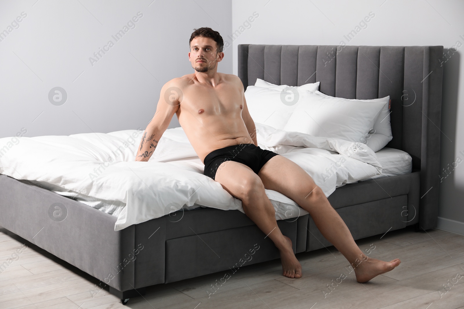 Young man in stylish black underwear on bed indoors Photo of Young man in stylish black underwear on bed indoors