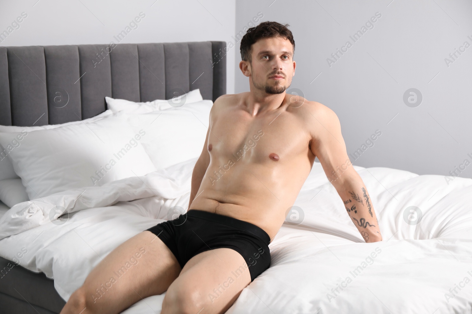 Young man in stylish black underwear on bed indoors Photo of Young man in stylish black underwear on bed indoors
