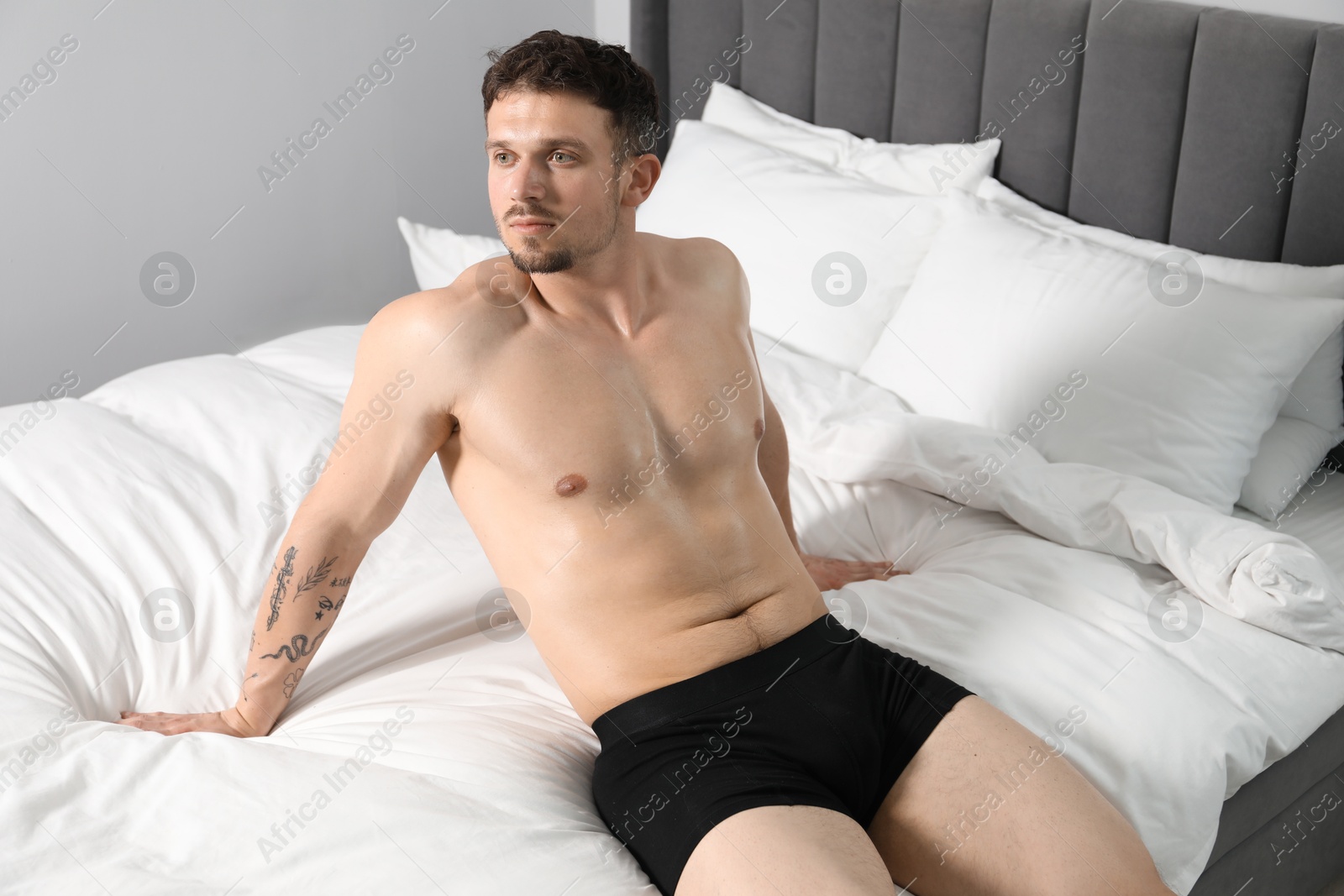 Young man in stylish black underwear on bed indoors Photo of Young man in stylish black underwear on bed indoors