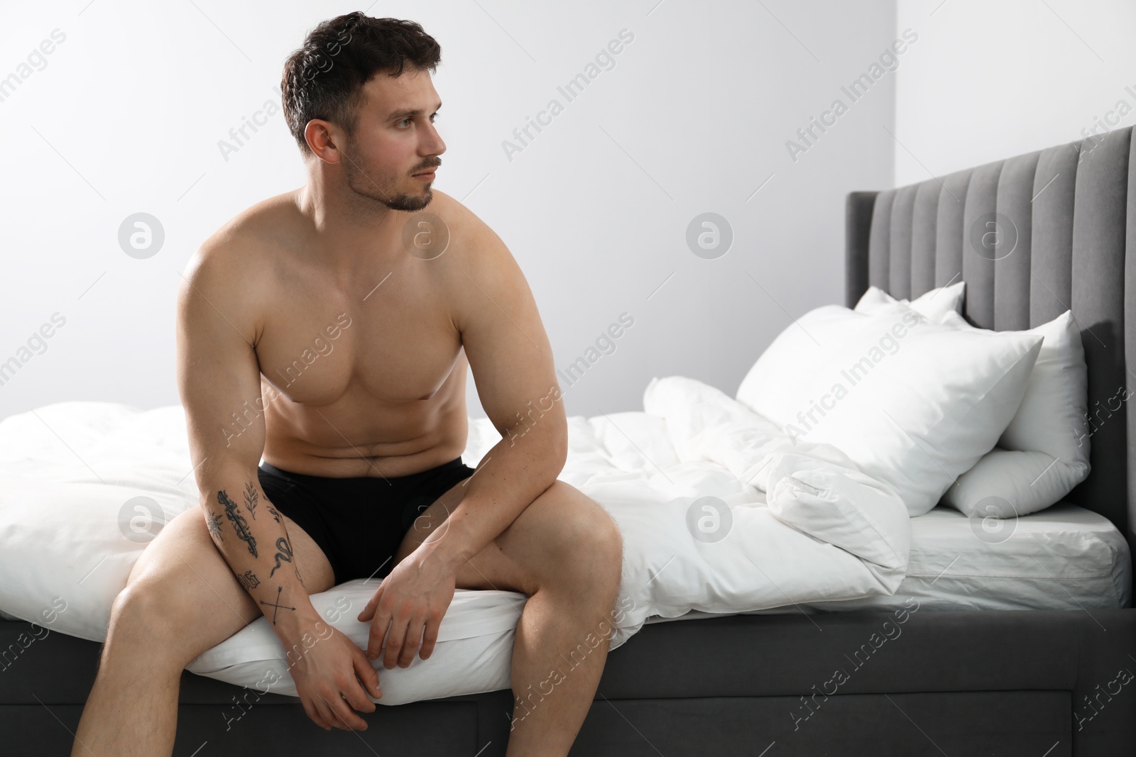 Young man in stylish black underwear on bed indoors. Space for text Photo of Young man in stylish black underwear on bed indoors. Space for text