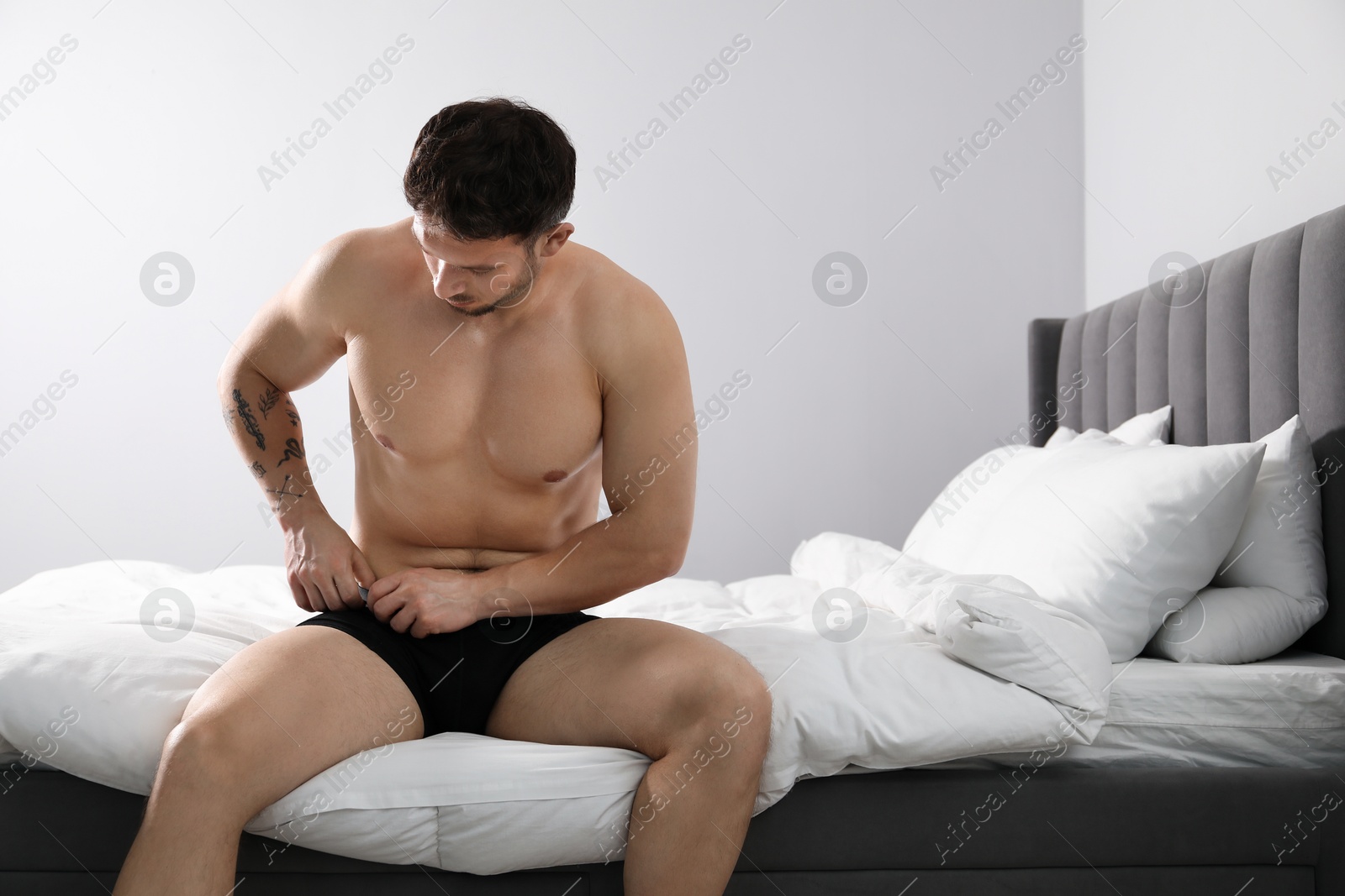 Young man in stylish black underwear on bed indoors. Space for text Photo of Young man in stylish black underwear on bed indoors. Space for text