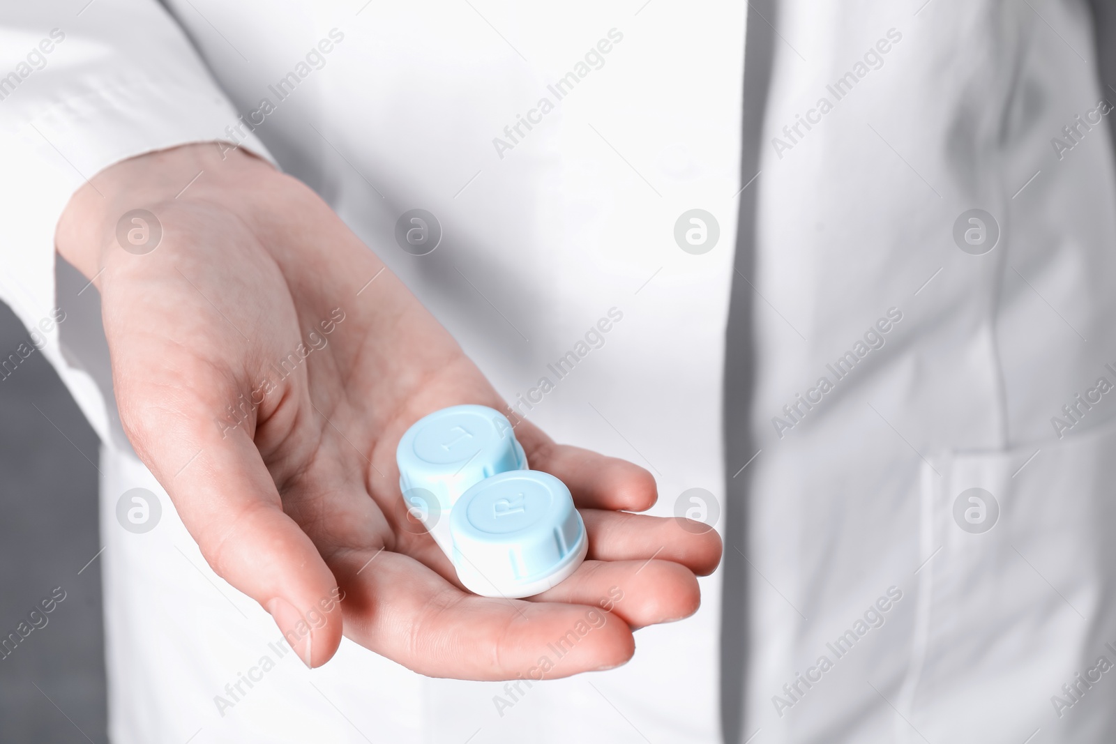 Doctor holding case with contact lenses on grey background, closeup Photo of Doctor holding case with contact lenses on grey background, closeup