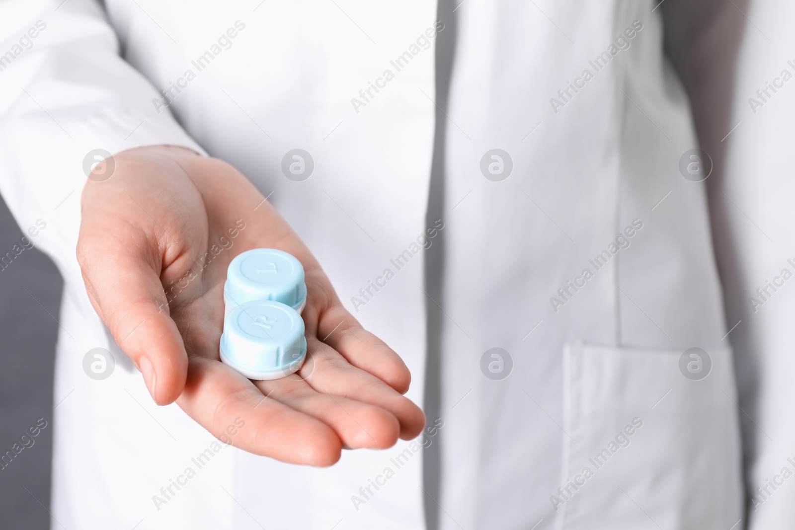 Doctor holding case with contact lenses on grey background, closeup Photo of Doctor holding case with contact lenses on grey background, closeup
