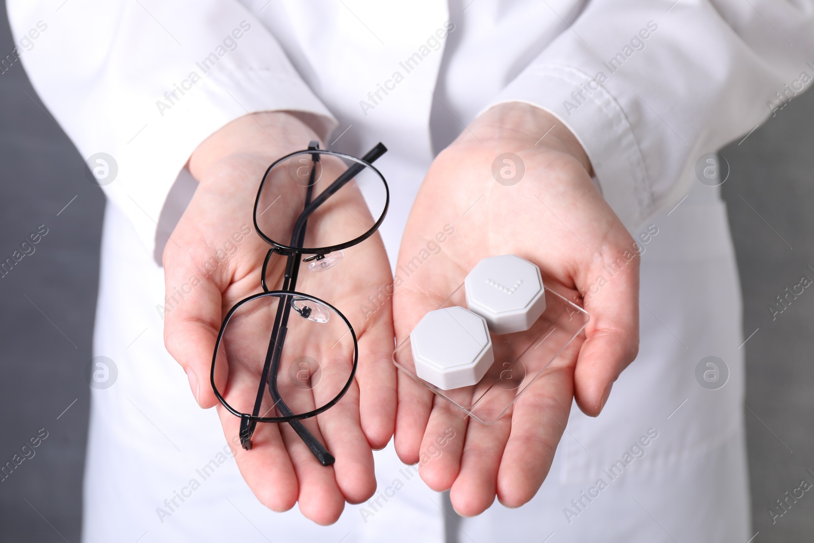 Doctor holding case with contact lenses and glasses on grey background, closeup Photo of Doctor holding case with contact lenses and glasses on grey background, closeup