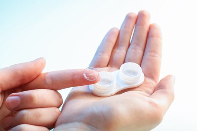 Photo of Woman with contact lenses on light background, closeup