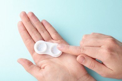 Photo of Woman with contact lenses on light blue background, closeup