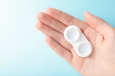 Photo of Woman with contact lenses on light blue background, closeup. Space for text