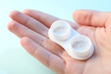 Photo of Woman with contact lenses on light blue background, closeup