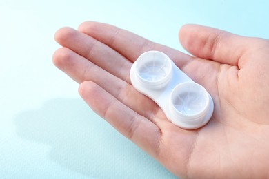 Photo of Woman with contact lenses on light blue background, closeup